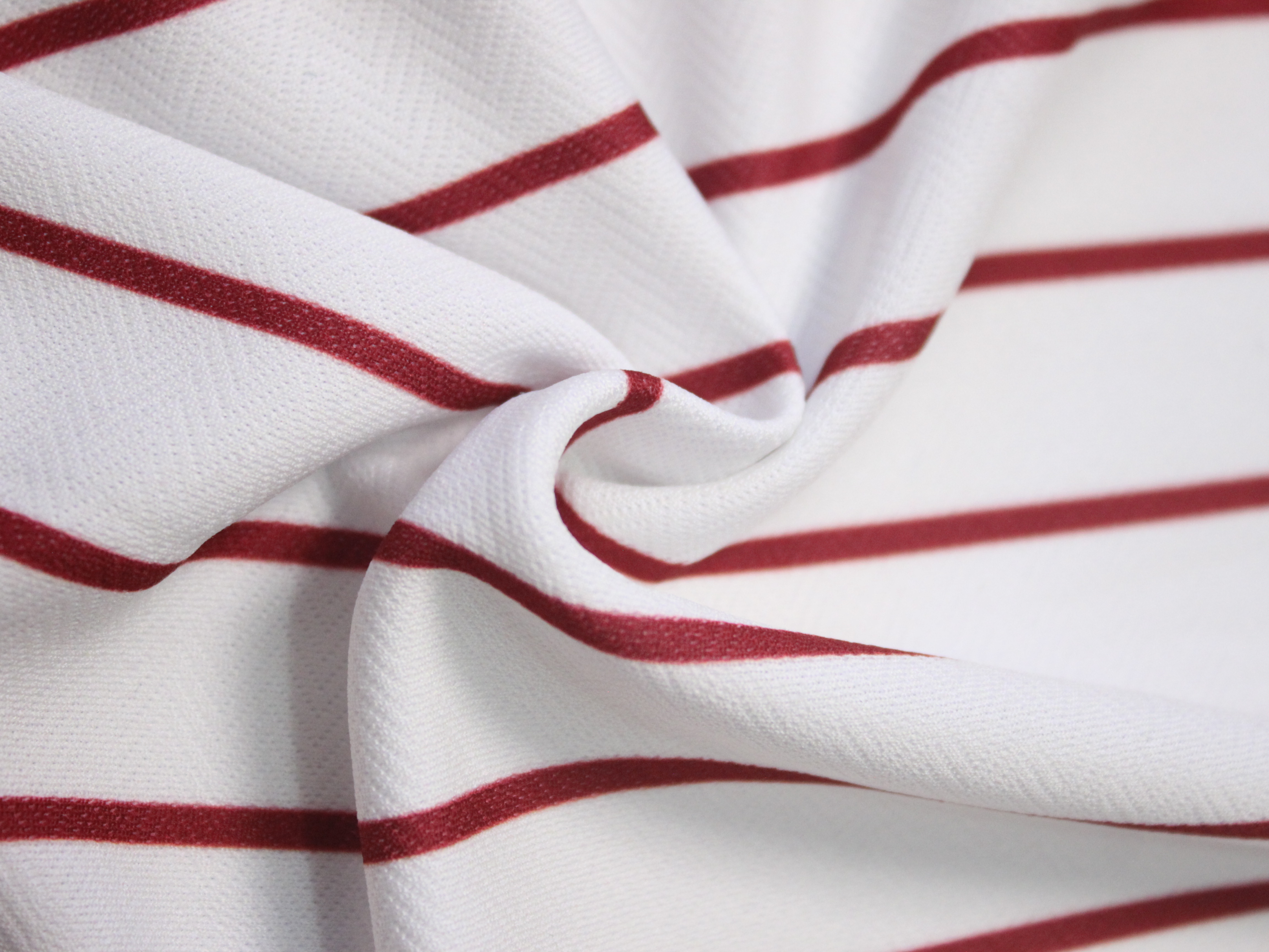 Kain jersey putih bergaris marun dipelintir memperlihatkan motif dan tekstur seratnya