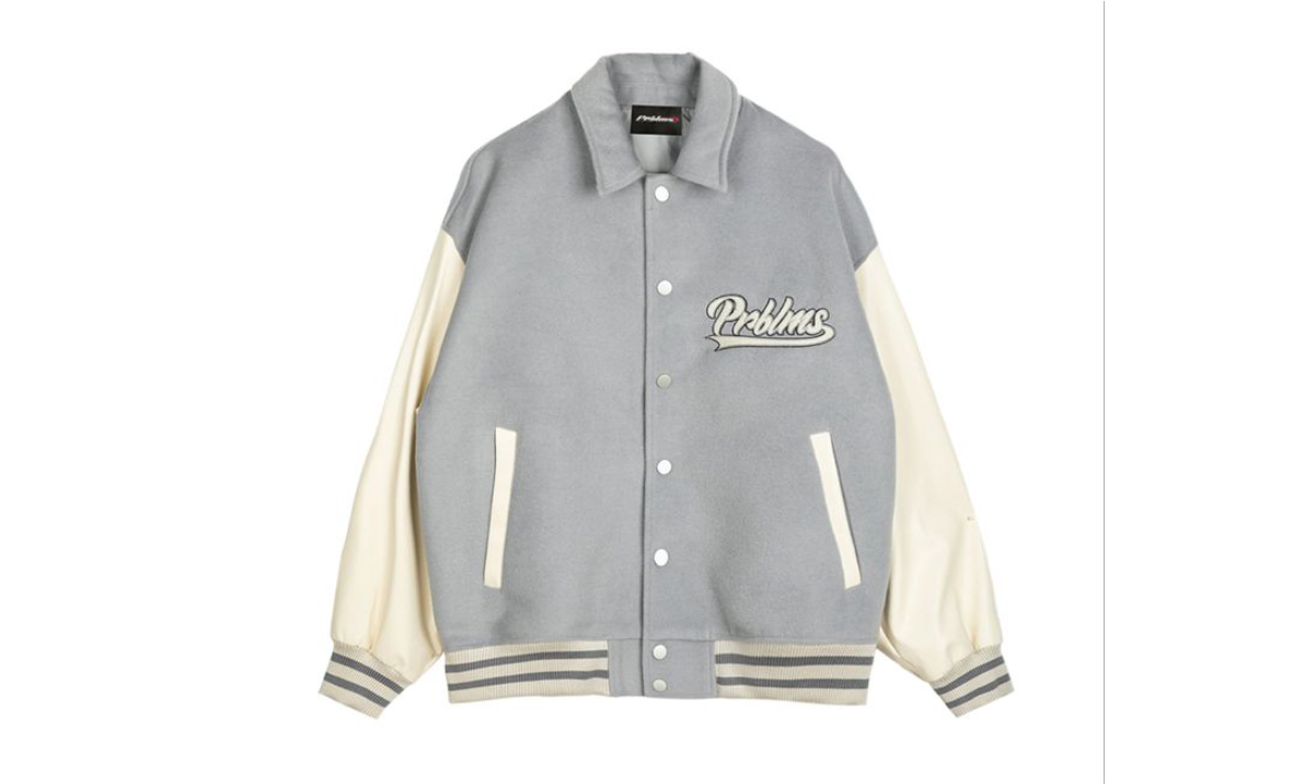 Jaket varsity abu-abu berlengan krem difoto rapi dari atas dengan rib bergaris di ujung lengan