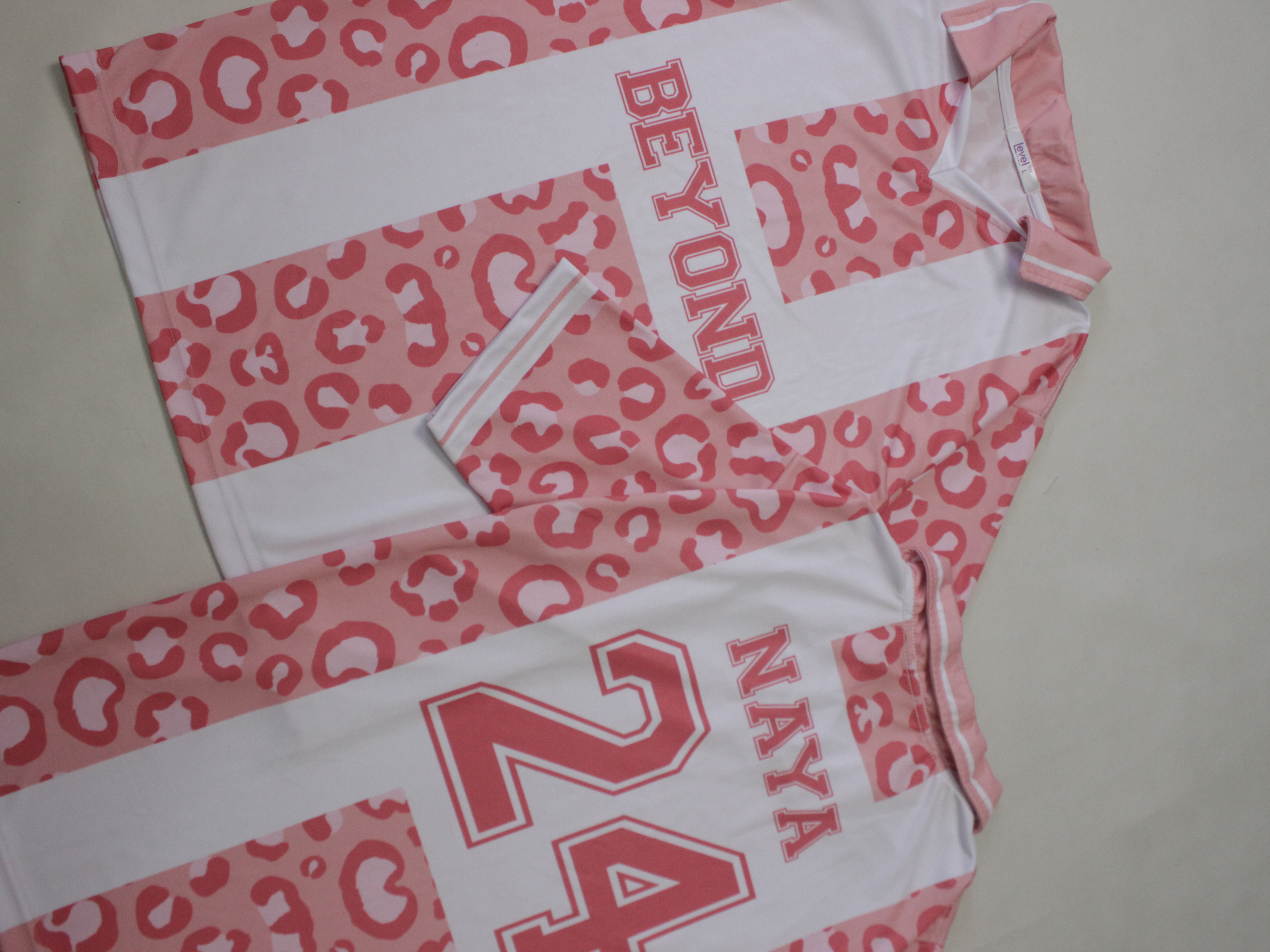 Jersey motif leopard dengan nama dan angka besar satu warna menempel di atas panel putih solid