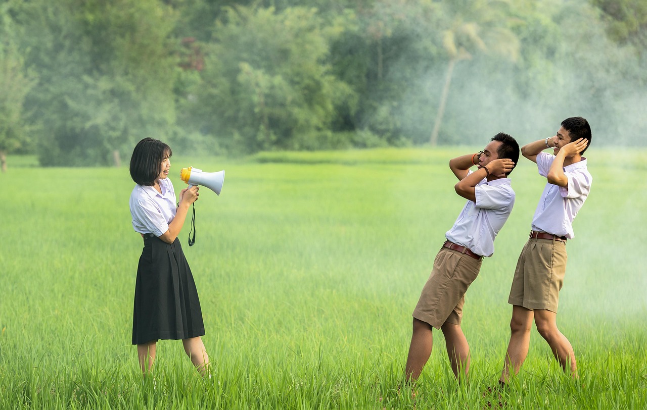 Siswa berseragam putih di lapangan hijau saat pagi berkabut, salah satunya berseru lewat pengeras suara
