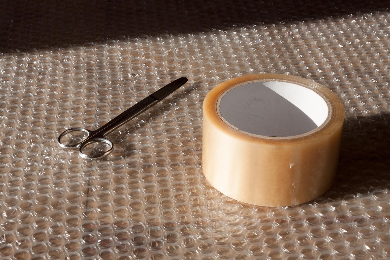 Gulungan isolasi, gunting, dan bubble wrap di meja packing