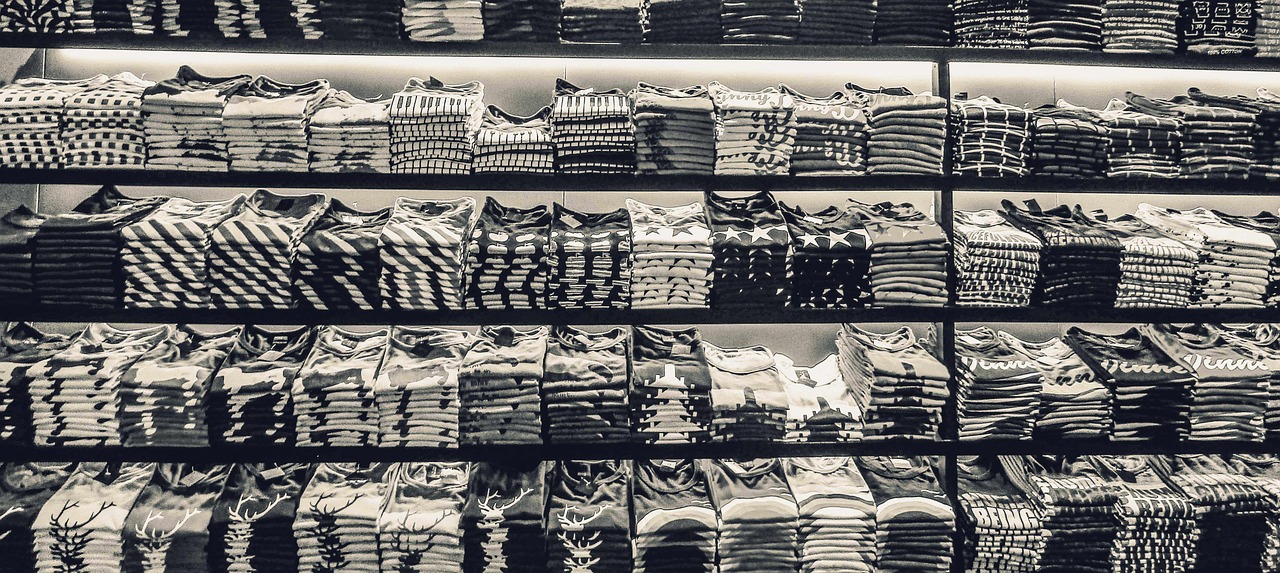 Tumpukan kaos sablon terlipat rapi berjajar dalam susunan rapat di rak