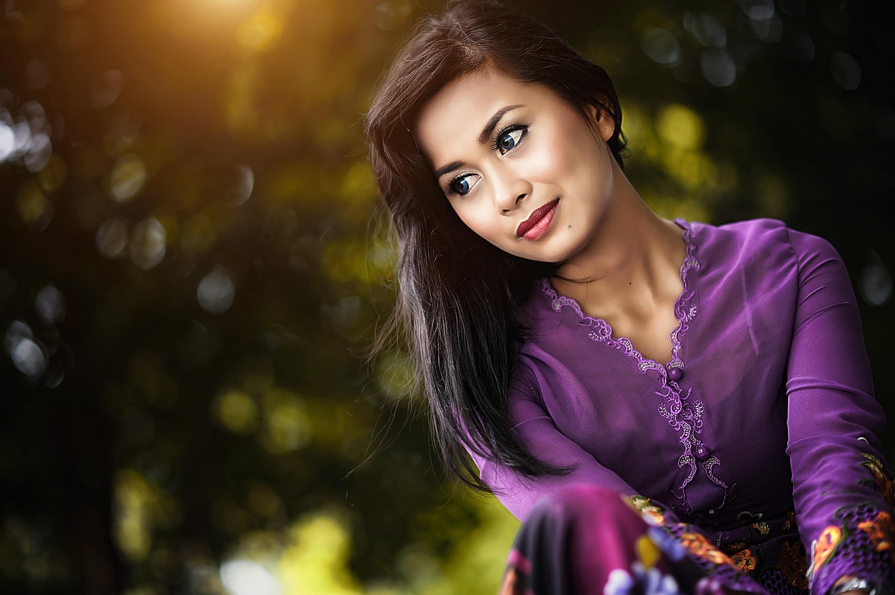 Perempuan mengenakan kebaya tradisional sambil tersenyum di luar ruangan