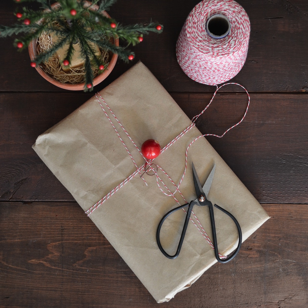 Paket kertas diikat tali, bersama gunting dan spul tali di meja kayu