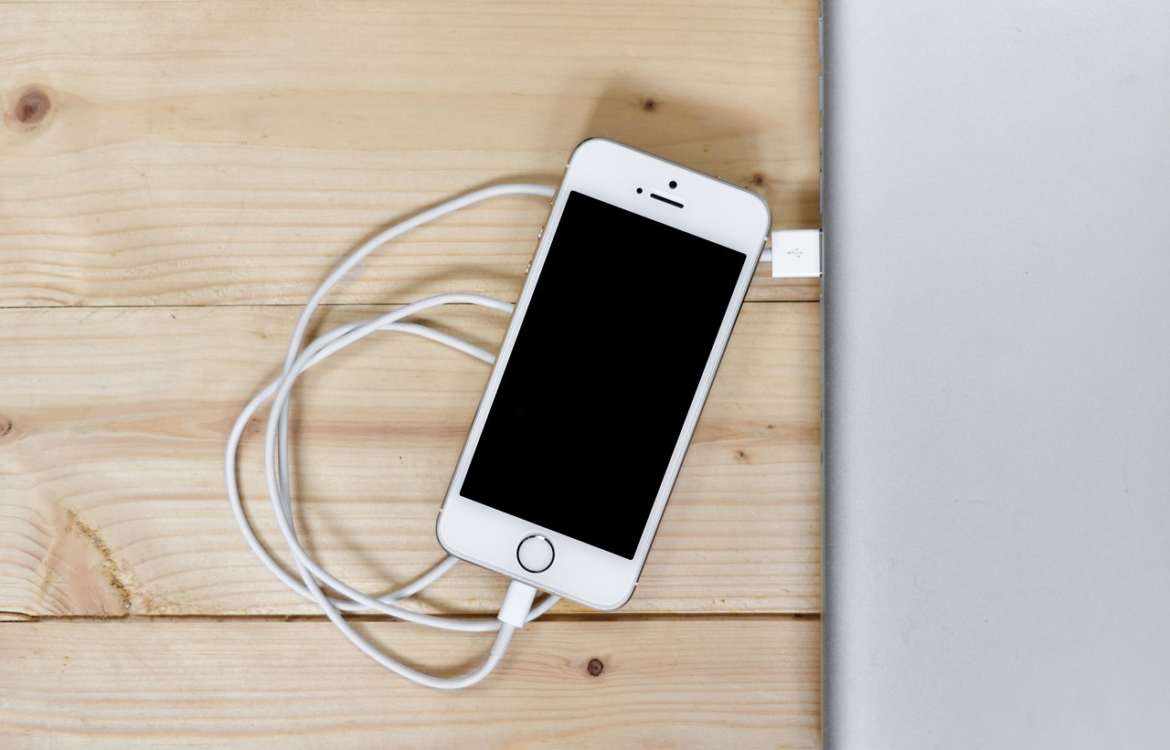 Ponsel diisi daya dengan kabel di atas meja kayu