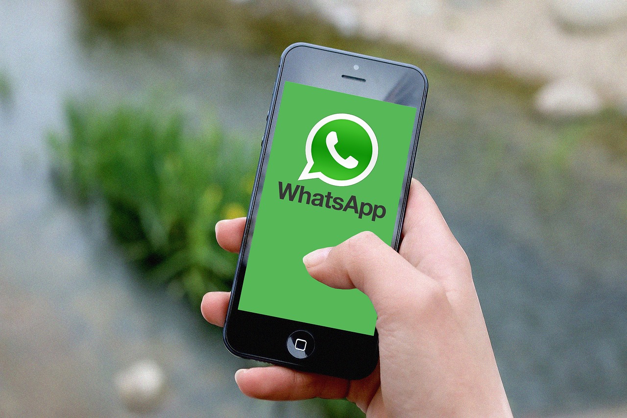 Tangan memegang ponsel yang menampilkan logo WhatsApp di layarnya