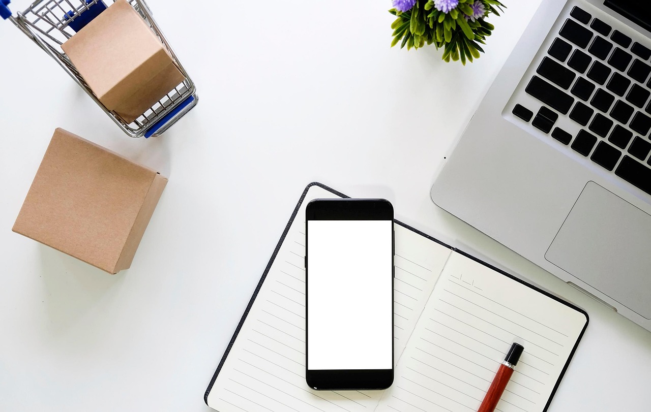 Meja kerja toko online dengan ponsel di atas buku catatan dan kotak paket